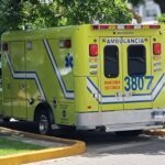 "Ambulancia amarilla y azul estacionada en una área de acceso público."